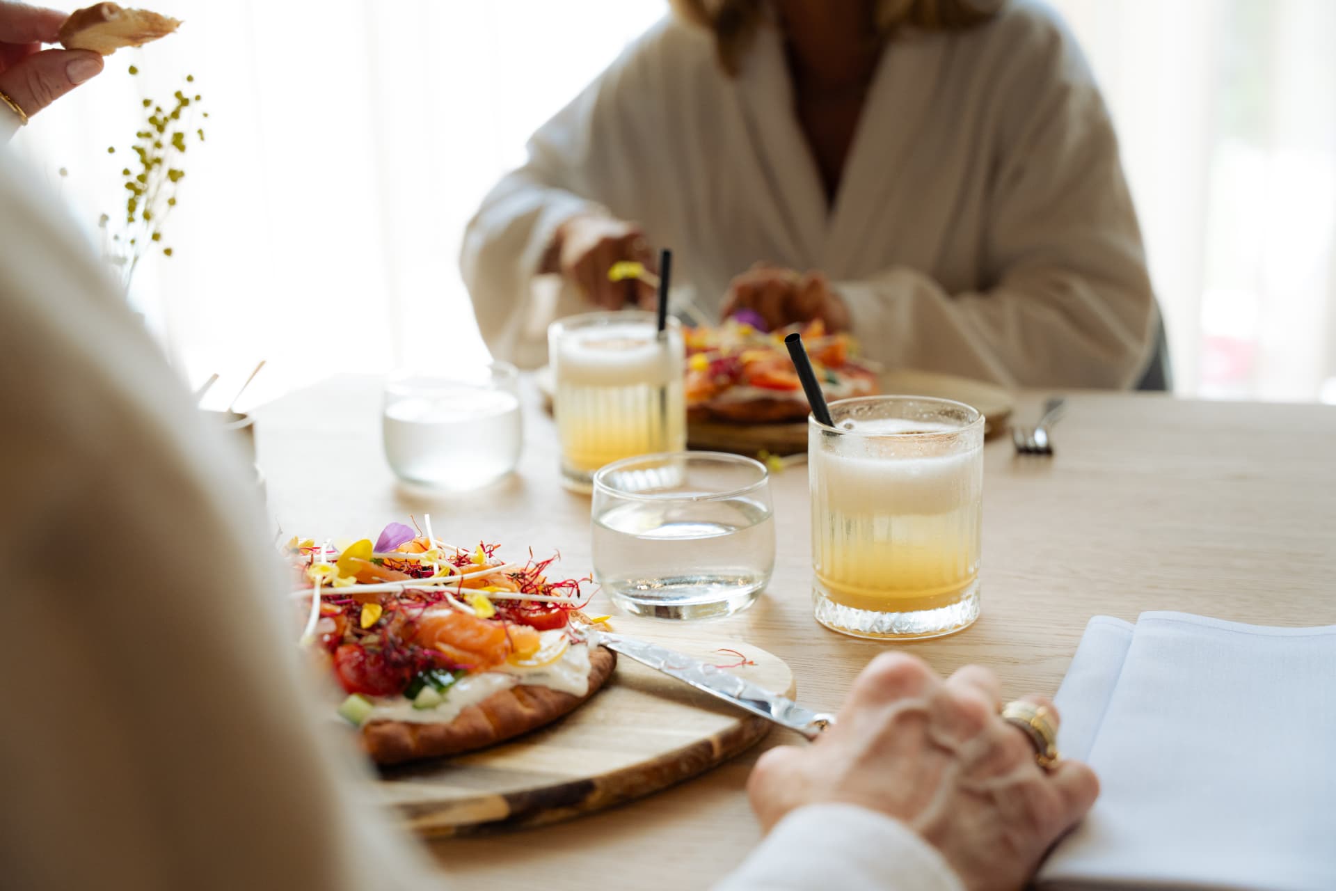 Gasten genieten in badjas van een verrassingslunch met een frisse drank