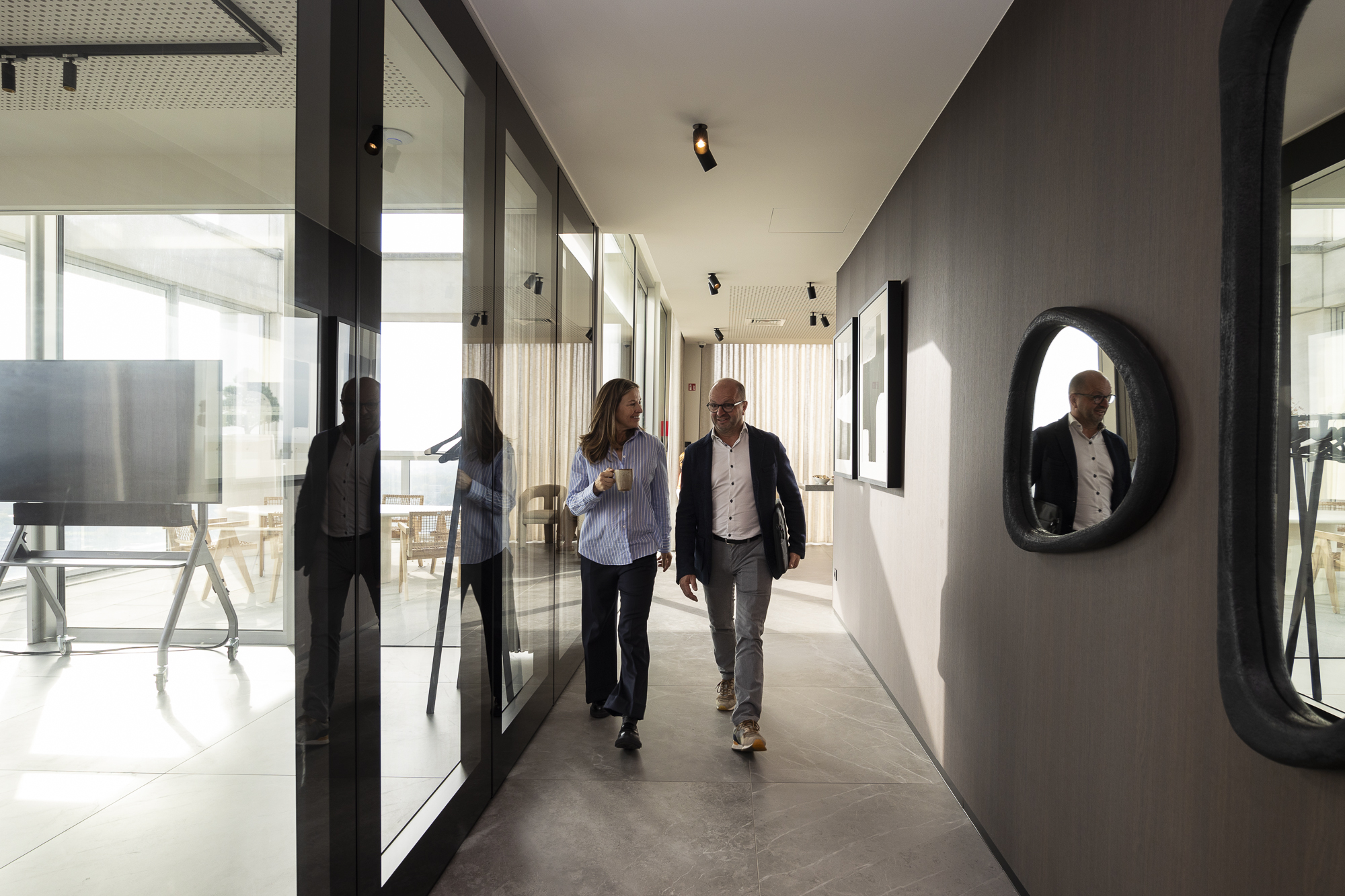 Corridor with glass-walled meeting rooms and daylight at Sky Venue