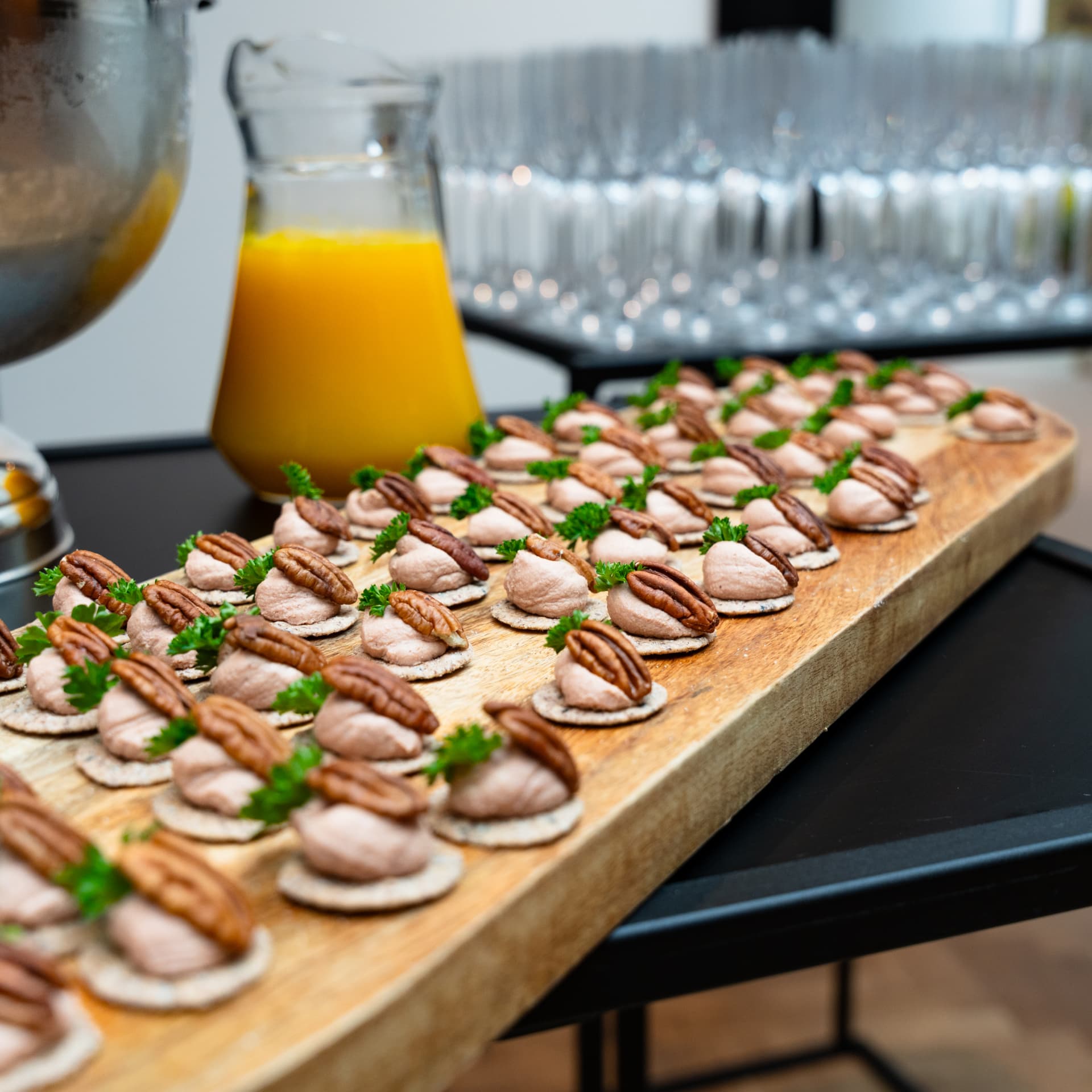 Hapjes met mousse en pekannoot naast een karaf verse jus d'orange