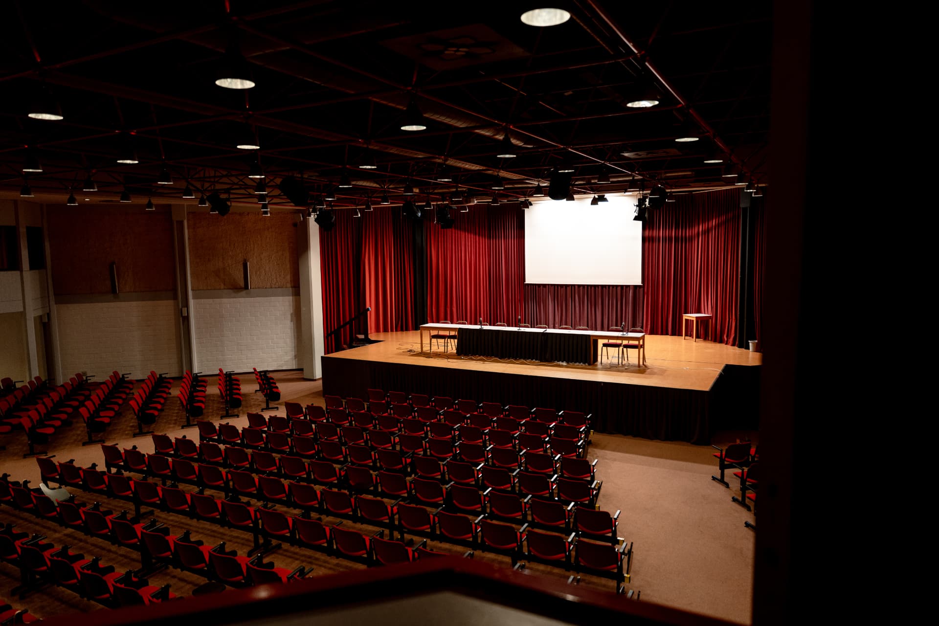 Concert hall with stage, projection screen and red seats