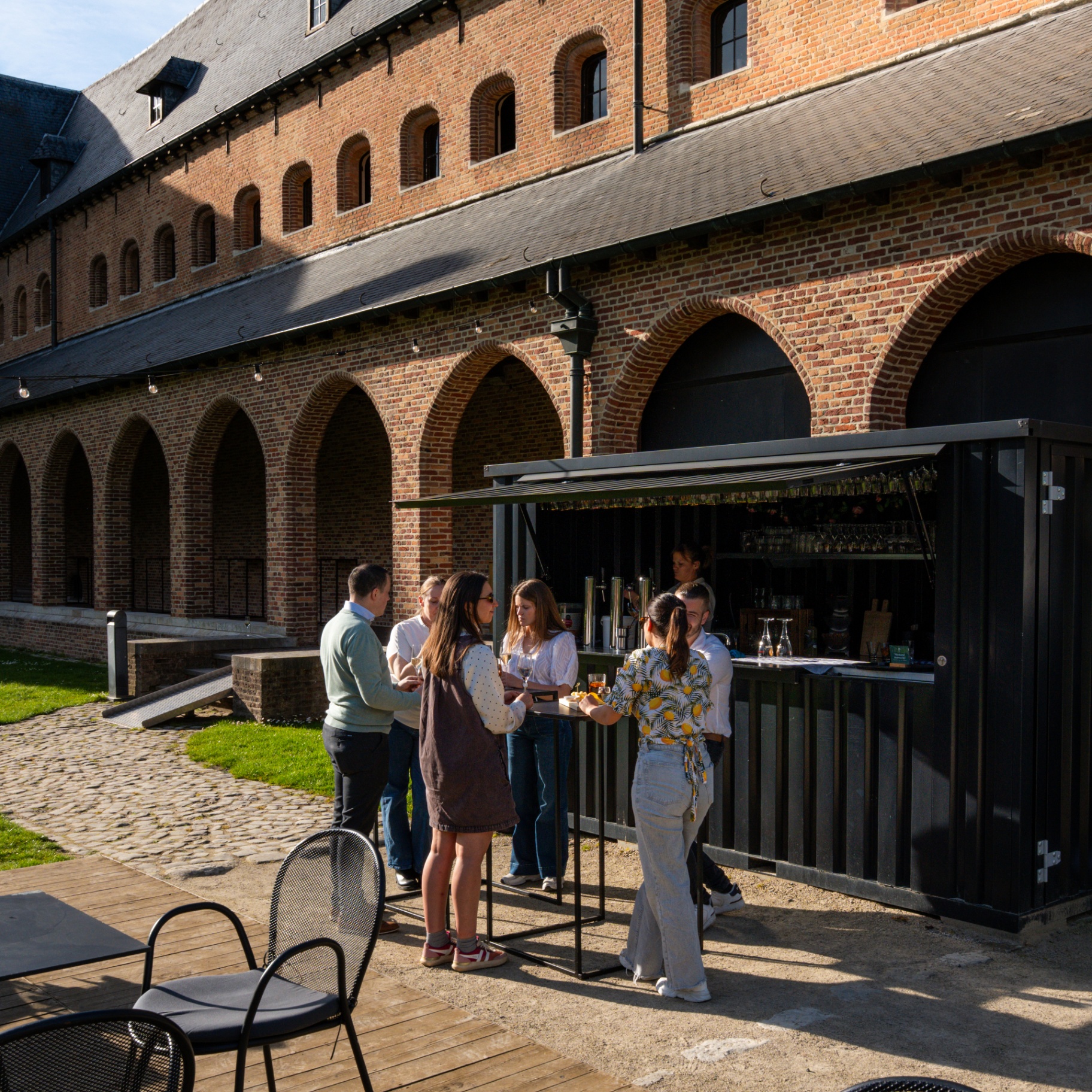 Gasten aan de zomerbar in de binnentuin van Priorij Corsendonk