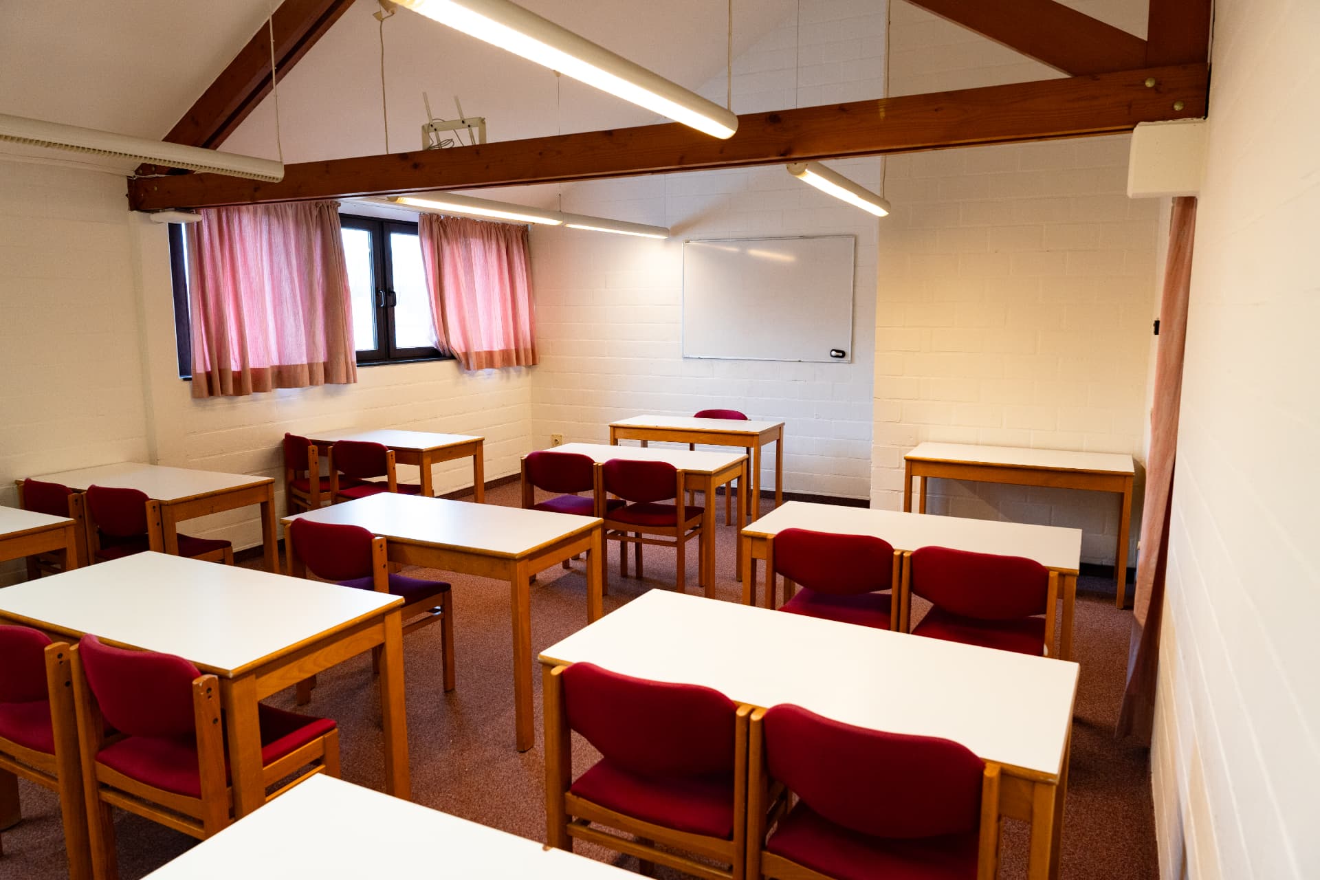 Meeting room with wooden roof beams and tables at Corsendonk Duinse Polders