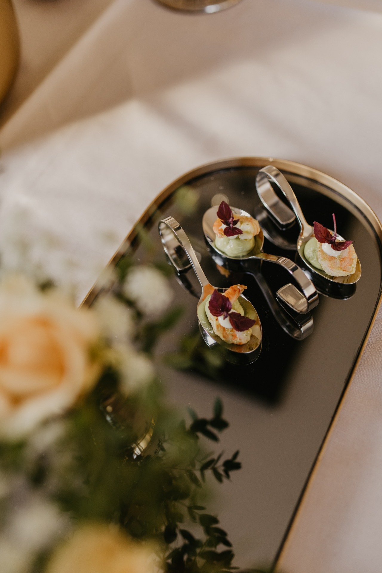 Appetizer spoons with scampi and avocado cream on a mirror plate