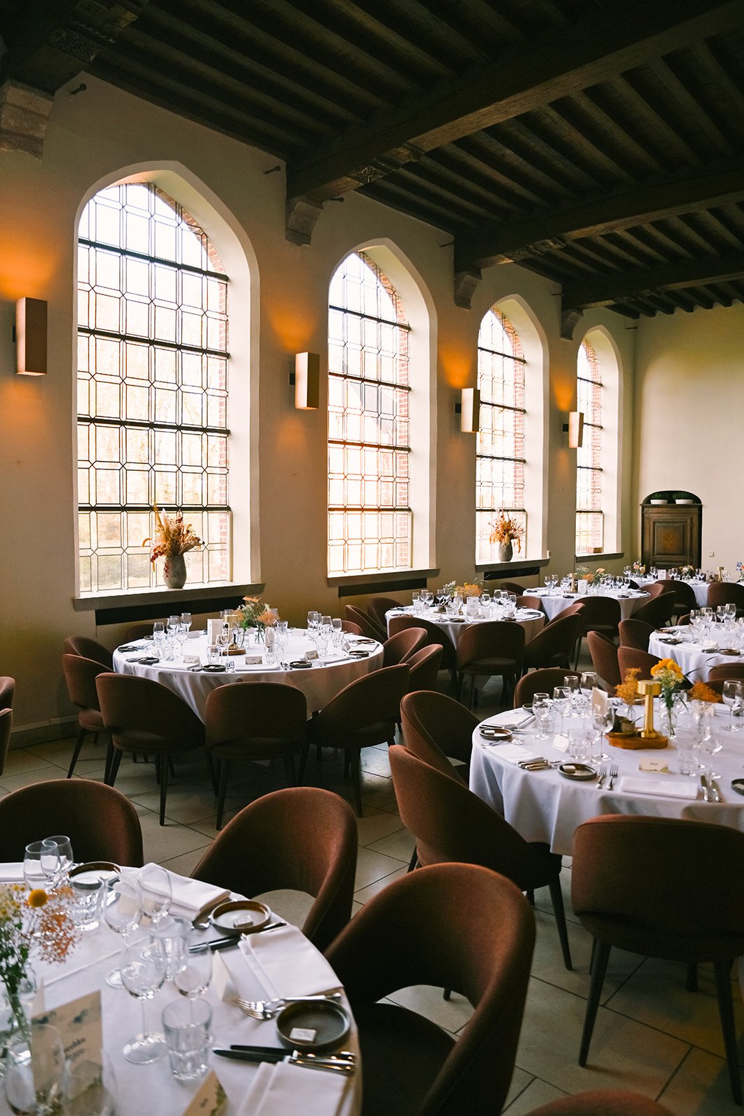 Set round tables near stained glass windows in Priorij Corsendonk