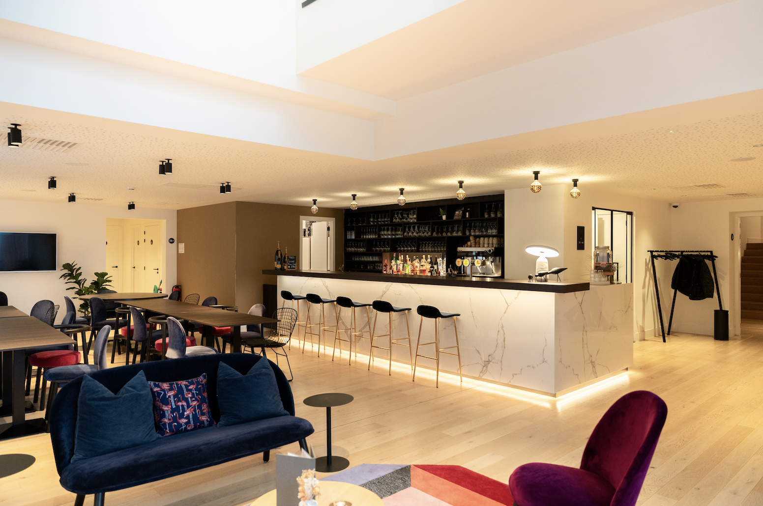 Overzicht van de lounge met marmeren bar, barkrukken en velours zetels bij Corsendonk Turnova