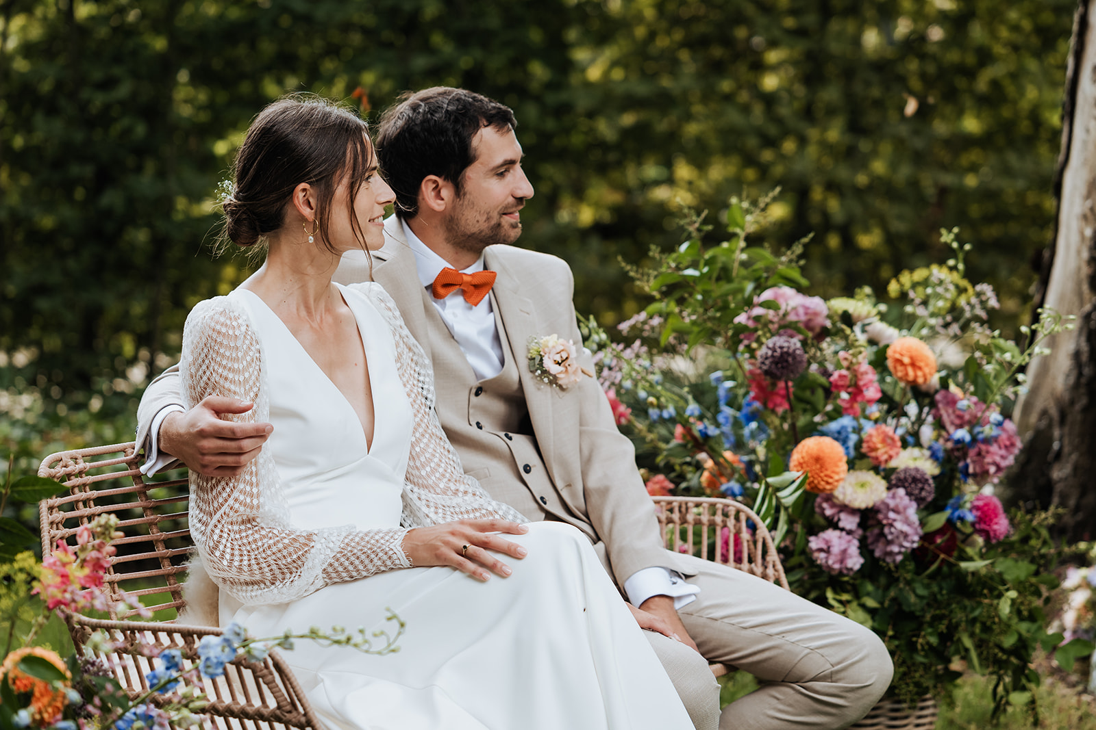 Bridal couple on a wicker bench among the flowers
