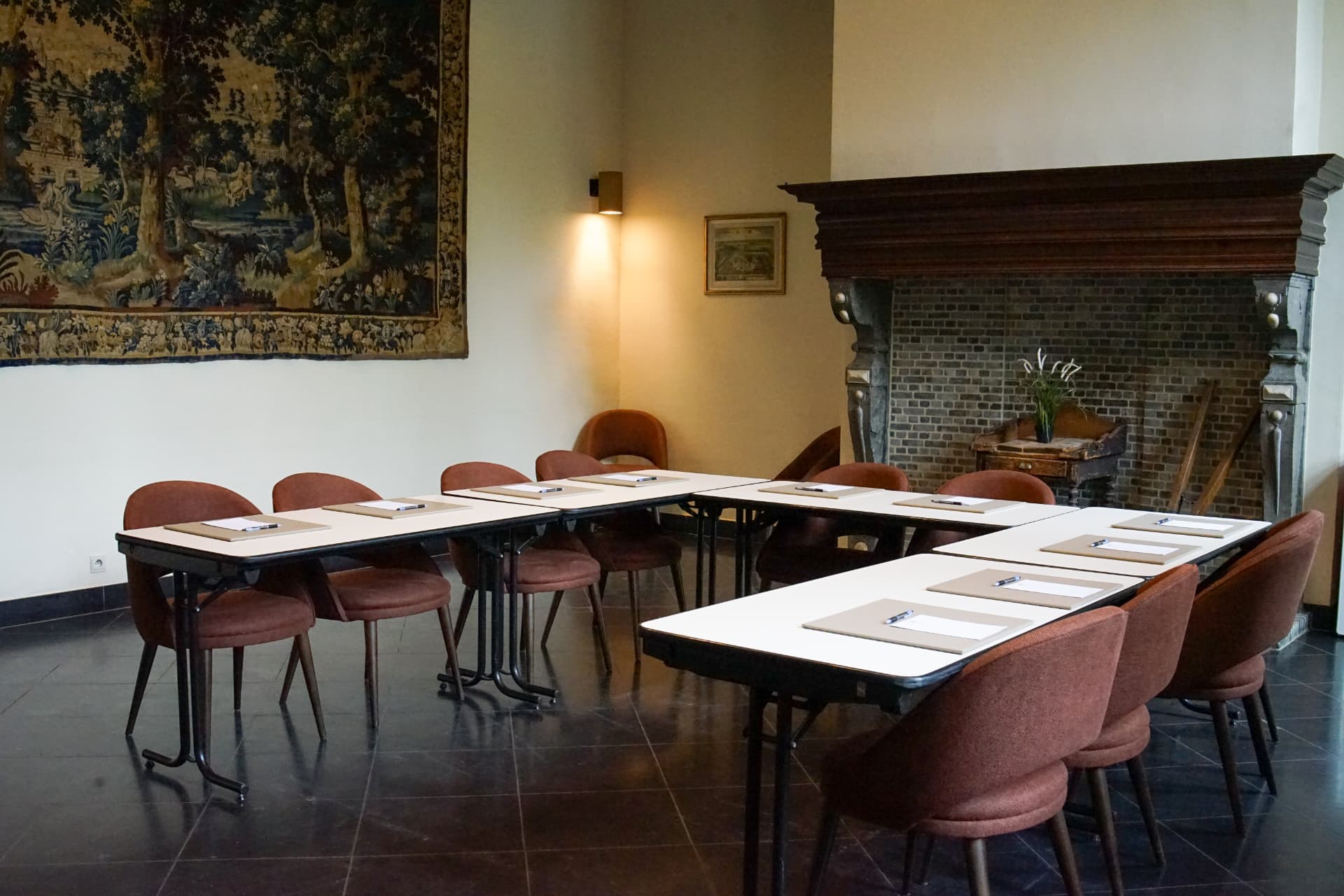 Vergadertafel opgesteld bij een historische schouw in een meetingzaal van Priorij Corsendonk