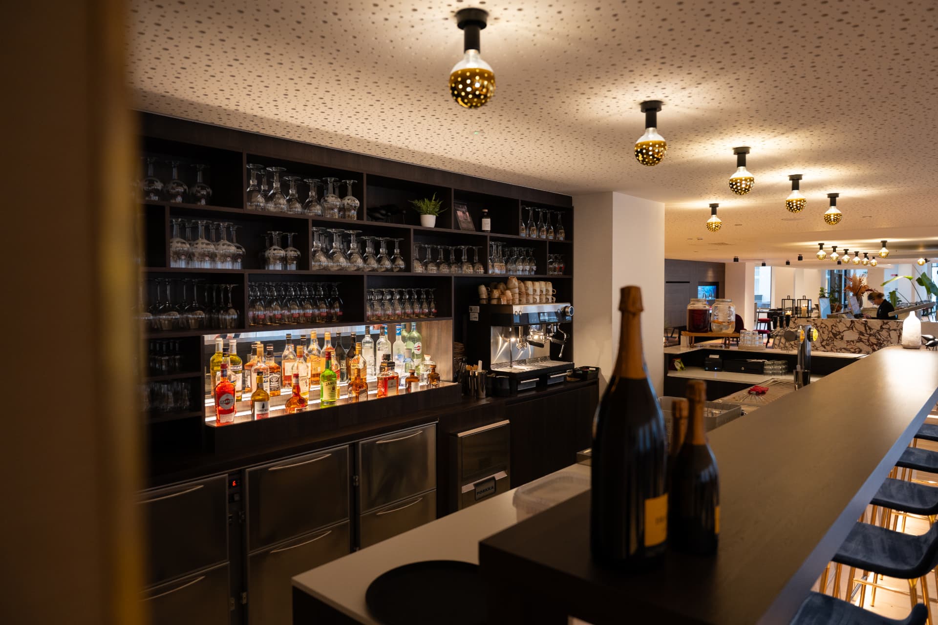 Sfeervolle bar met verlichte drankenwand en champagneflessen bij Corsendonk Turnova