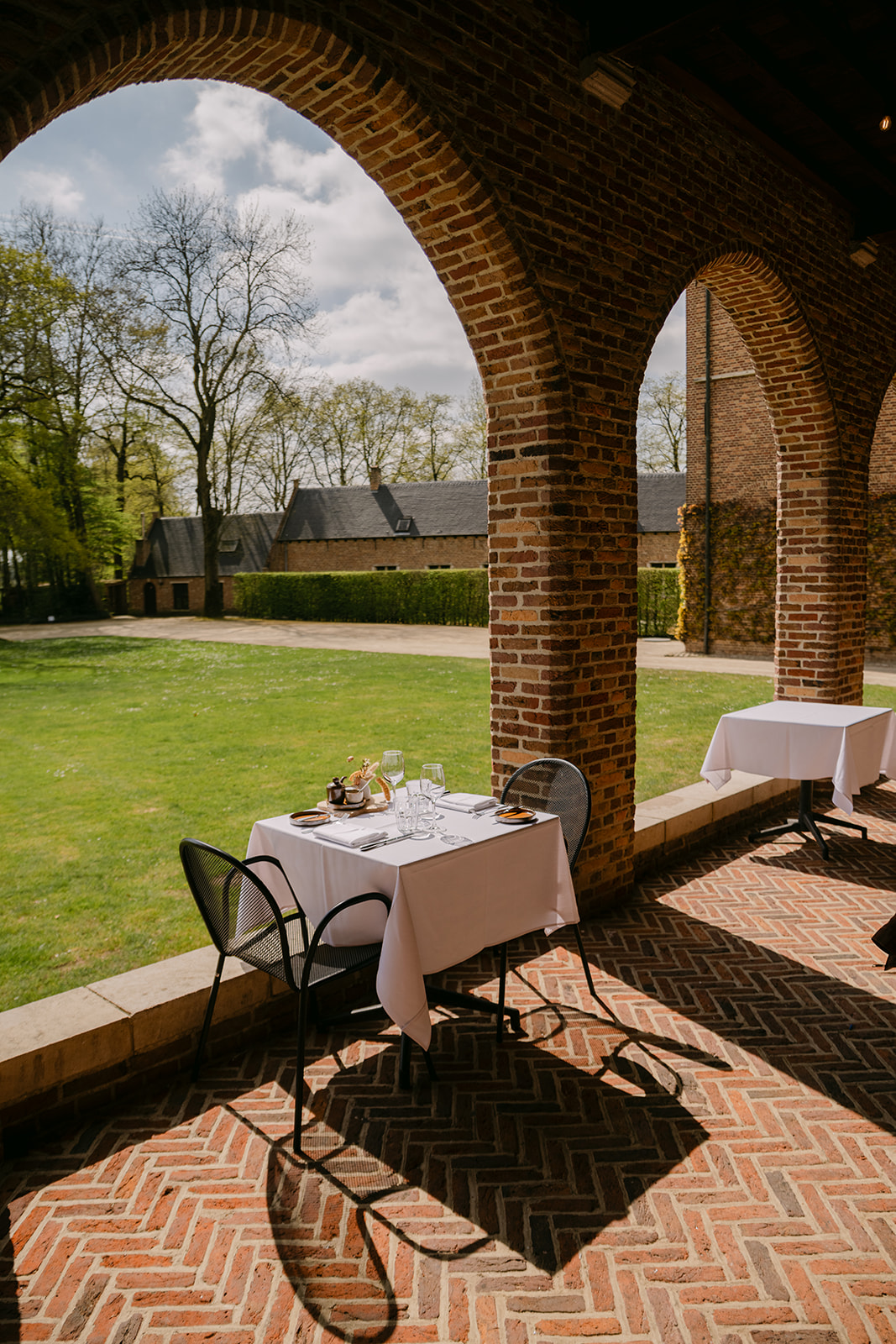 Table set under the arcade with a view of the garden at Priorij Corsendonk